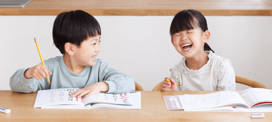 放課後等デイサービスで楽しく学習支援を受ける小学生の男女