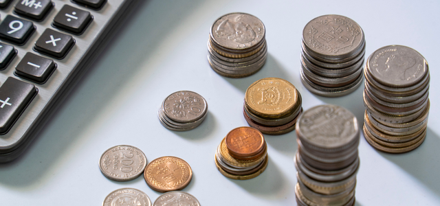 保険代理店システムの費用相場やコスト構成をイメージした硬貨と電卓