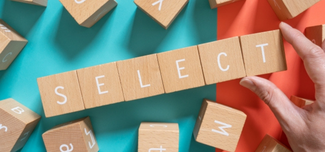木製ブロックで「SELECT」と並べられた文字を手で持つ様子